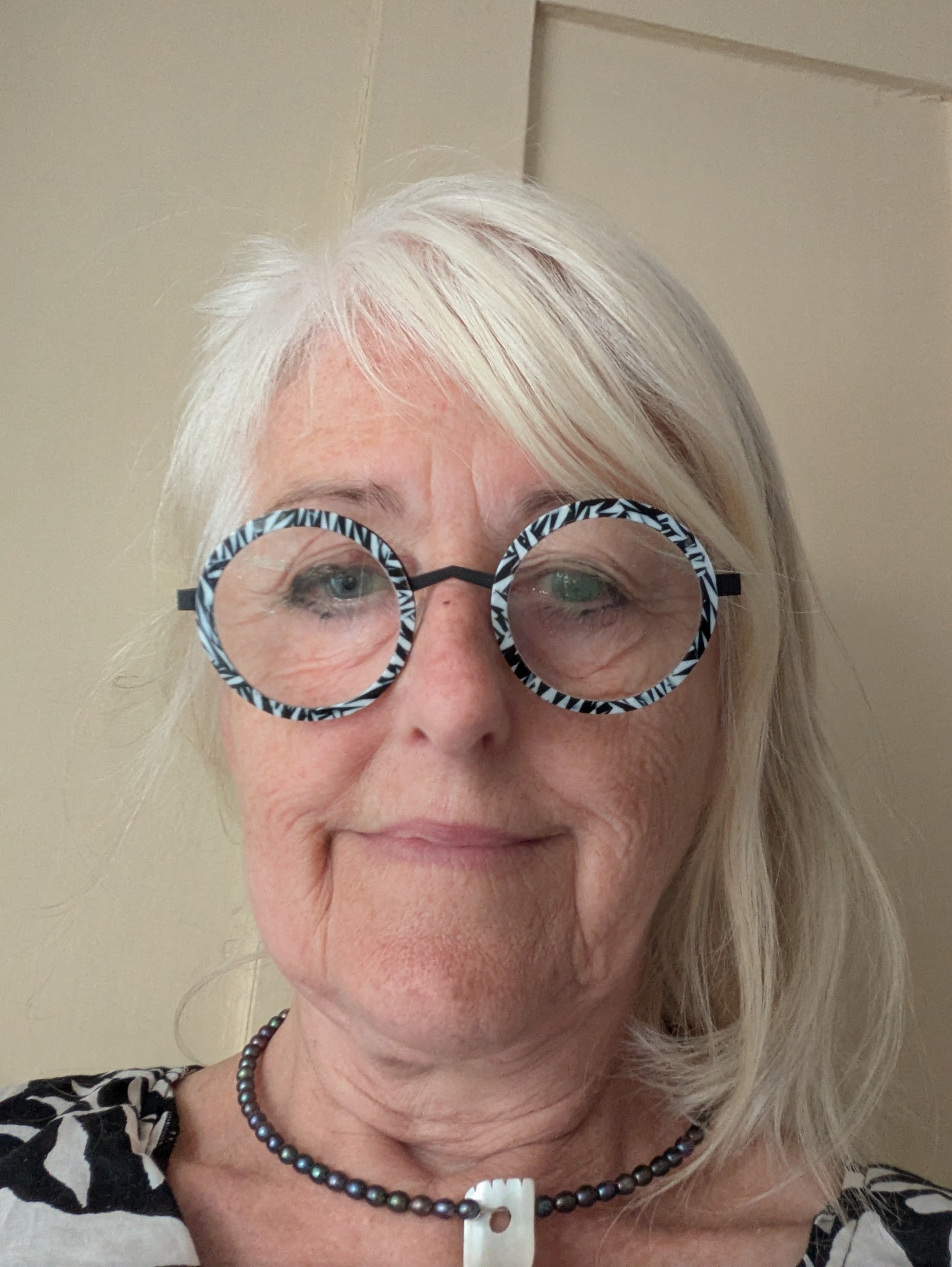 Woman wearing a pair of round, patterned glasses against a plain background